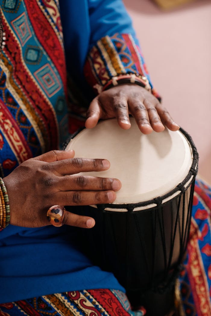 our-services-3 Hands playing a djembe drum, wearing colorful traditional attire, highlighting cultural and musical heritage.